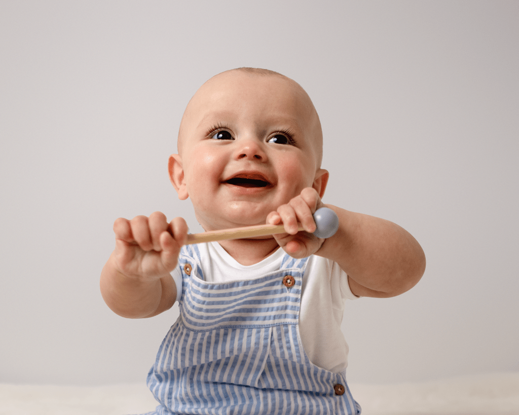 a happy, smiling baby having fun with a wooden toy