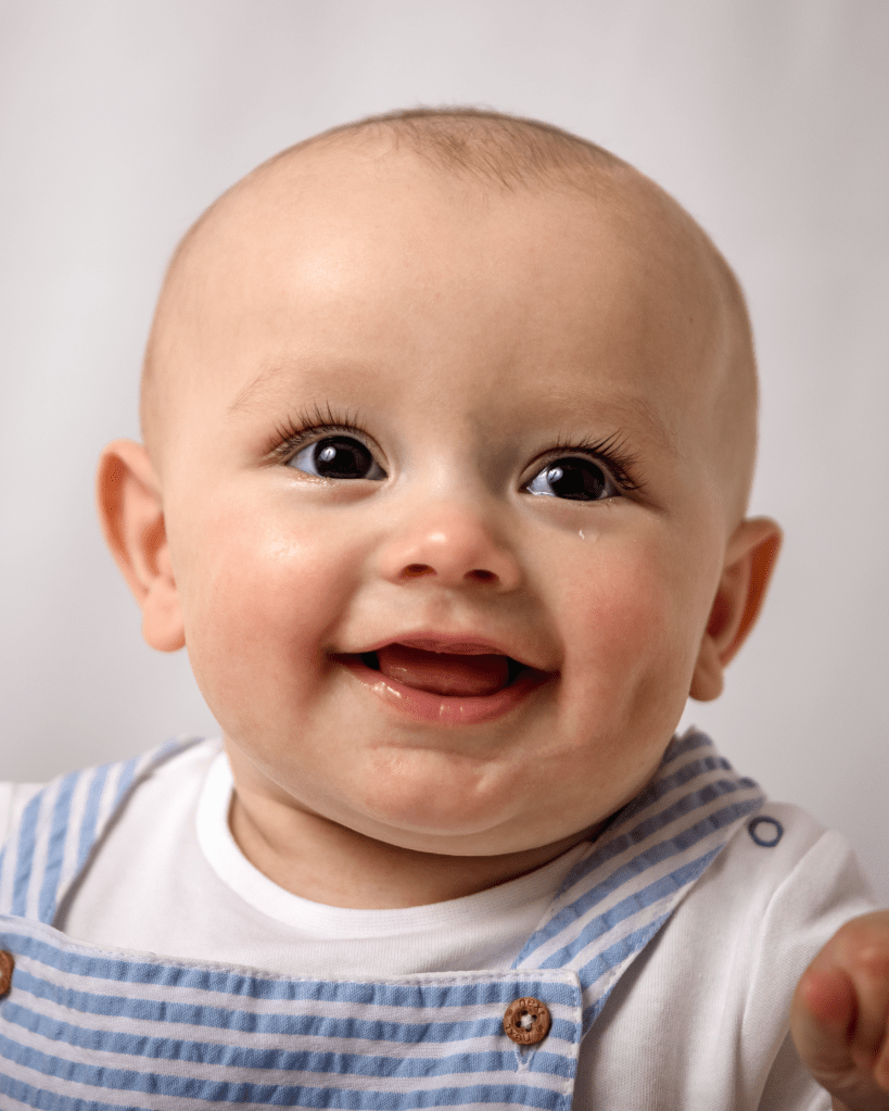 a close up of a smiling baby sticking its tongue out