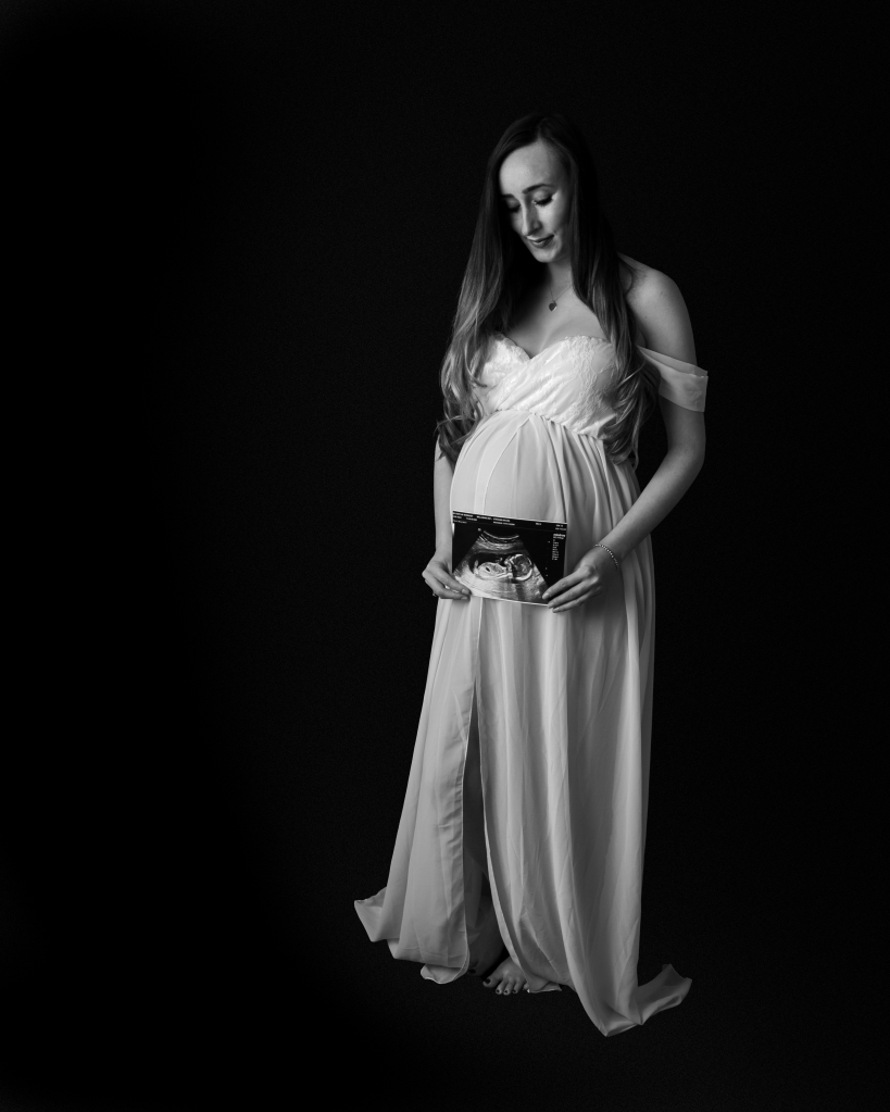 new mother holding a foetal scan over her bump