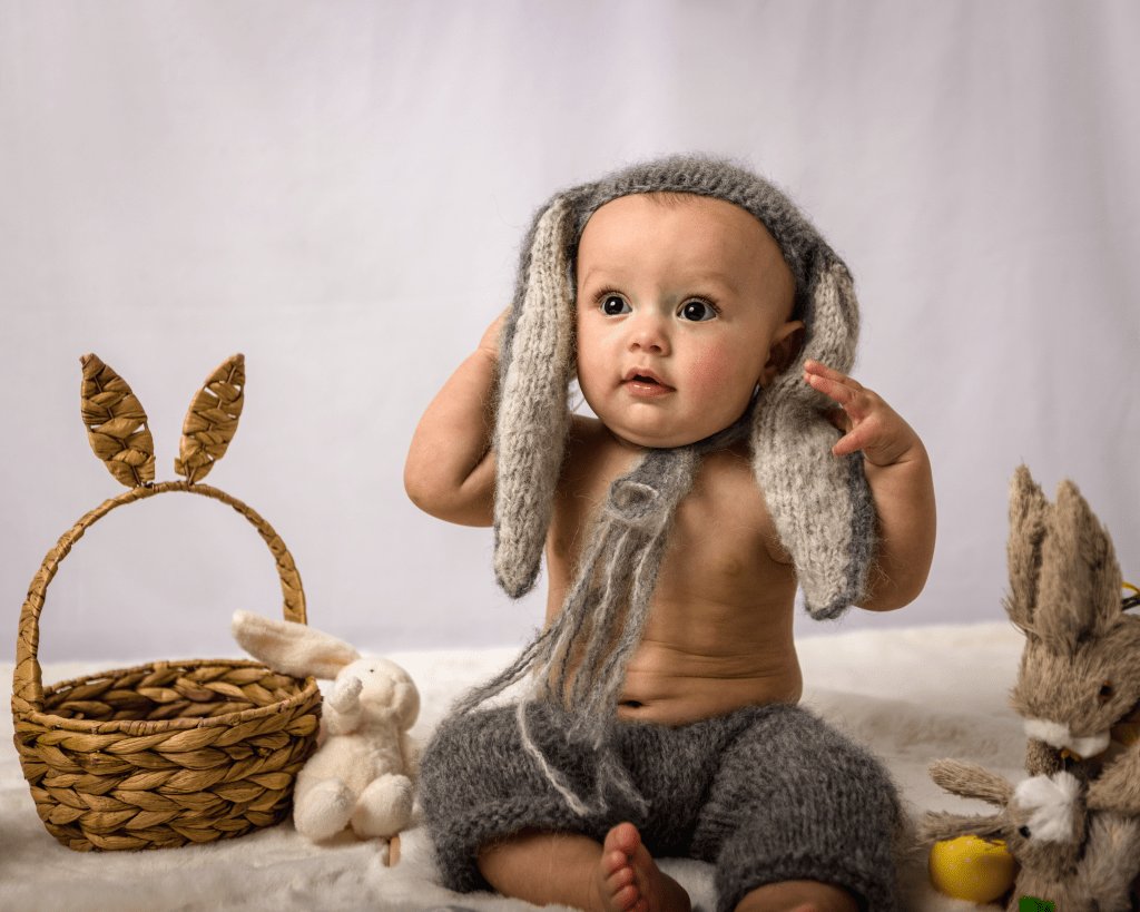 a little baby boy wearing a hat of knitted rabbit ears