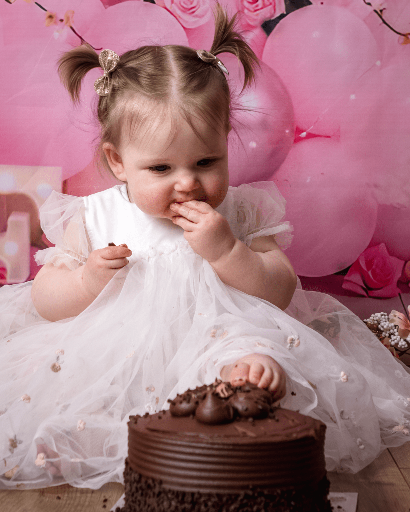 the little girl places her left foot on top of the chocolate cake