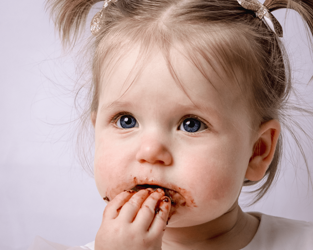a little girl has chocolate cake all around her mouth