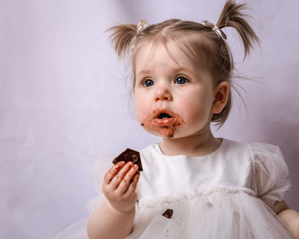 a little girl has chocolate cake in her hand