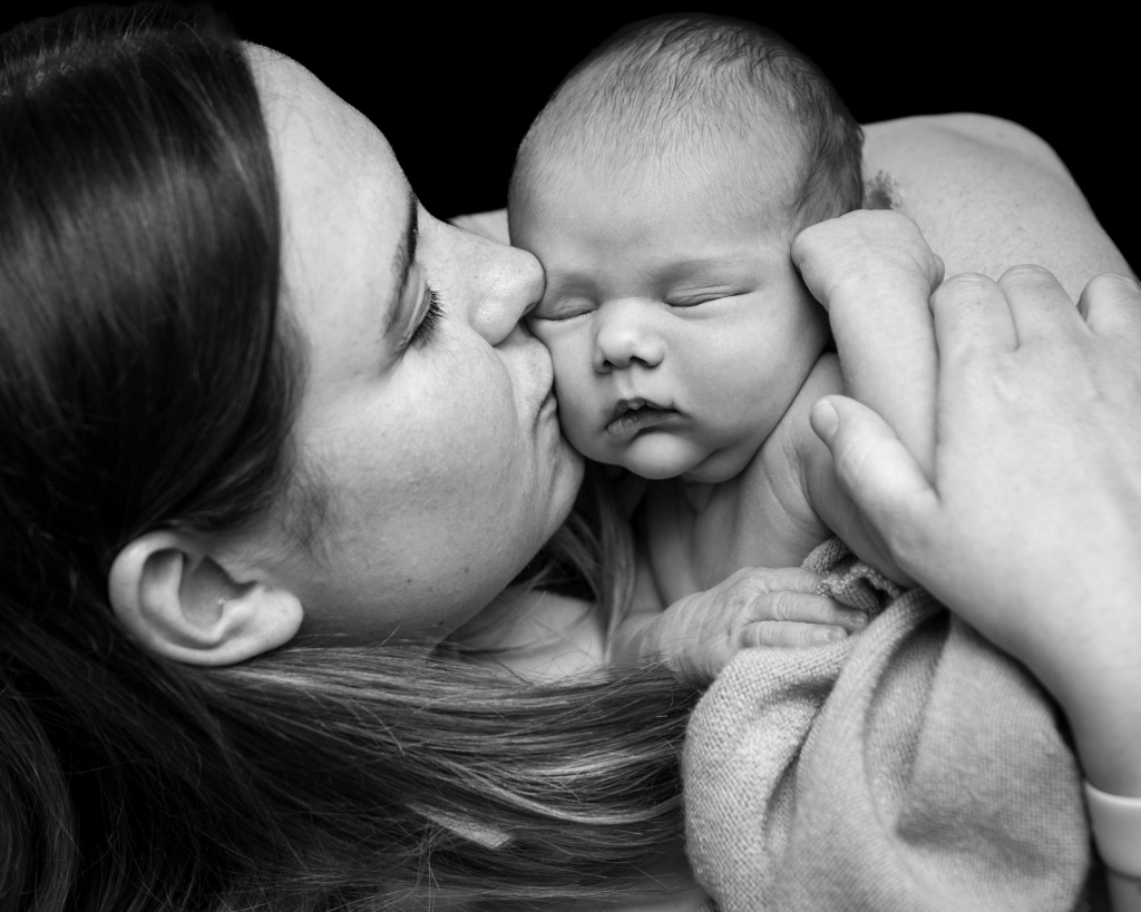 A new mother kisses her new born baby gently on the cheek