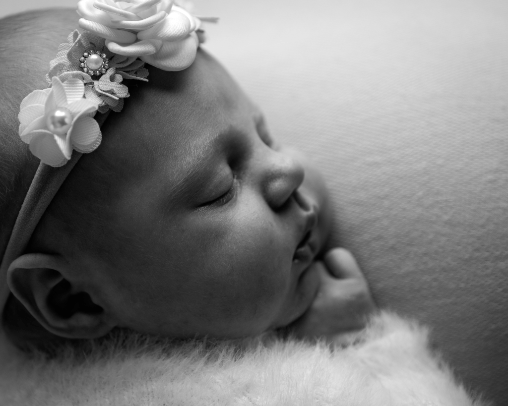 sleeping baby with headband on cushion. Black and white