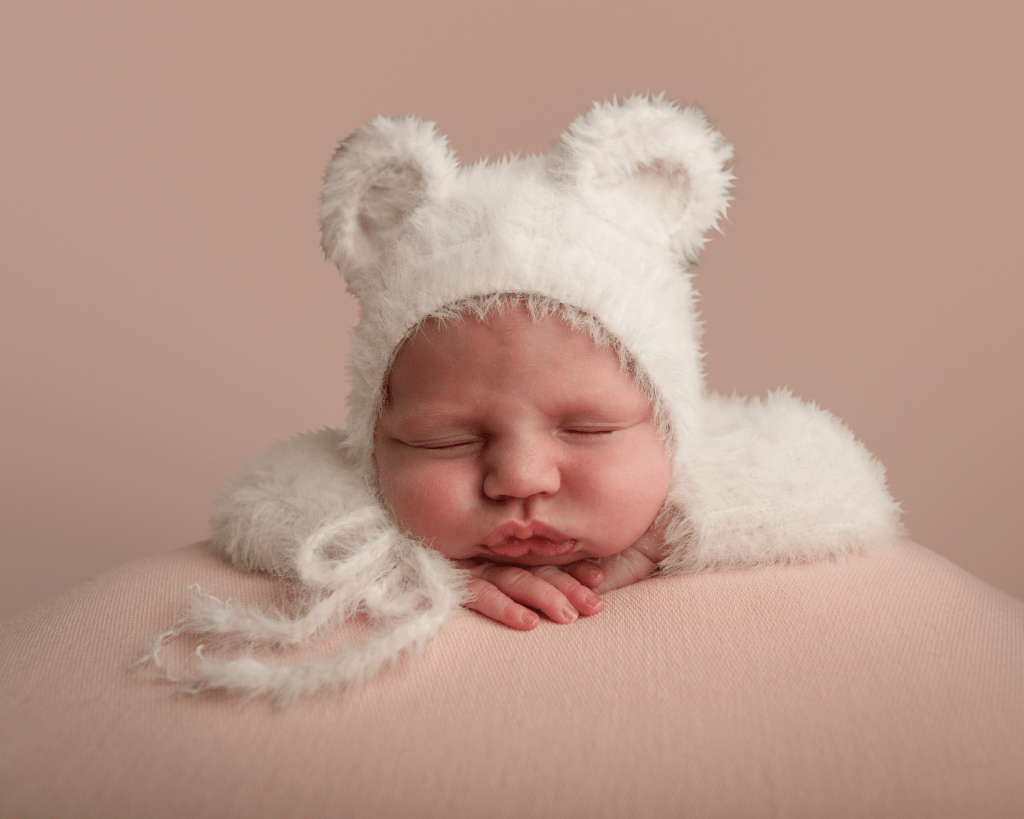 Little baby asleep in a white fluffy bear outfit